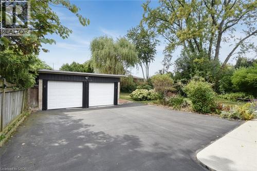 Two-car garage with white doors, asphalt driveway, and mature landscaping - 154 Ewen Road, Hamilton, ON 