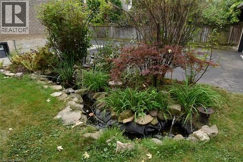 Water feature with rock border, surrounded by mature plantings and a manicured lawn - 154 Ewen Road, Hamilton, ON 