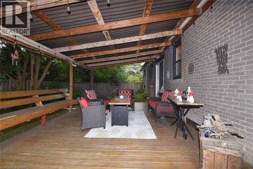 Expansive wooden deck featuring a covered patio with a corrugated roof, exposed wood beams, and string lighting - 154 Ewen Road, Hamilton, ON 