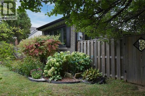 Brick exterior, window with awning, mature landscaping, wood privacy fence, decorative gate insert - 154 Ewen Road, Hamilton, ON 
