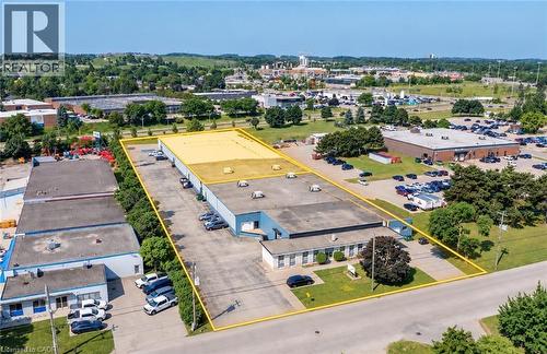 Industrial building with a flat roof, asphalt parking lot, and surrounding green landscaping - 97 Ardelt Avenue, Kitchener, ON 