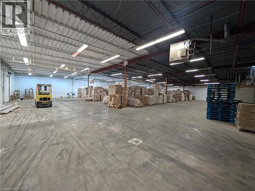 Expansive concrete flooring in a large open warehouse space with exposed structural beams and overhead fluorescent lighting - 97 Ardelt Avenue, Kitchener, ON 