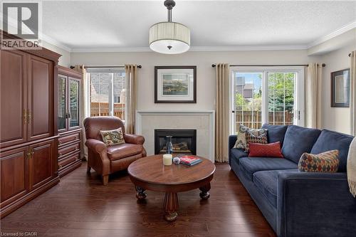 Living area featuring rich wood-finish flooring, a white mantel fireplace, crown molding, and a sliding glass door to the exterior - 1347 Brookstar Drive, Oakville, ON 