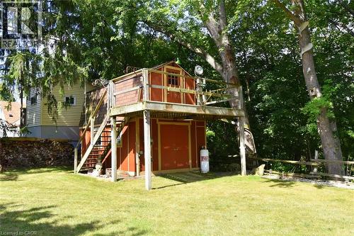 Expansive backyard featuring a manicured lawn, a two-story shed structure with an elevated deck, and mature trees providing natural screening - 781 Oakdale Avenue, Burlington, ON 
