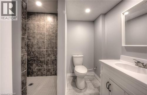 Tile-surrounded shower, white vanity with integrated sink, rectangular mirror, recessed lighting, and tile flooring - 33 Ruskview Road Unit# Lower, Kitchener, ON 