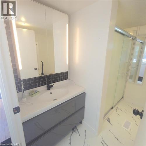 Modern vanity with integrated sink, black tile backsplash, and mirrored medicine cabinet with integrated lighting - 580 Beaver Creek Road Unit# Lot 158, Waterloo, ON 