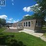 Expansive outdoor deck with multiple levels, vinyl siding exterior, multiple windows, and a gravel patio area - 580 Beaver Creek Road Unit# Lot 158, Waterloo, ON 