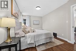 Wood-finish flooring with white baseboards, a window with sheer curtains, and a flush mount ceiling light - 