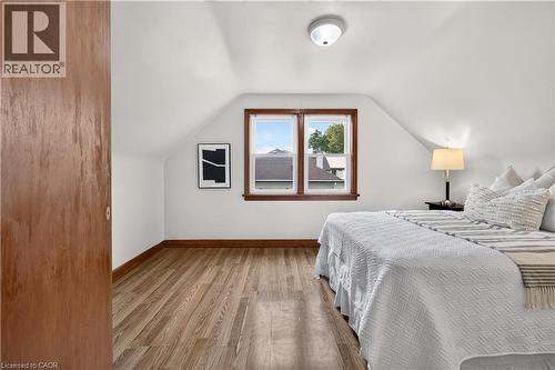 Attic space with wood-finish flooring, white walls, and a window with wood trim - 176 Avalon Place, Kitchener, ON 