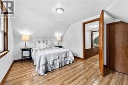 Wood-finish flooring, white walls, angled ceiling, wood trim, and a flush mount ceiling light - 