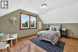 Sloped white ceiling with recessed lighting, green wall accent, wood-finish flooring, and white-framed windows with natural wood trim - 