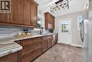 Wood cabinetry, stone-look countertops, glass mosaic tile backsplash, stainless steel appliances, and a glass-paneled door - 176 Avalon Place, Kitchener, ON 