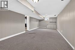 Finished lower level featuring neutral wall paneling, recessed lighting, built-in cabinetry, and patterned carpeting - 