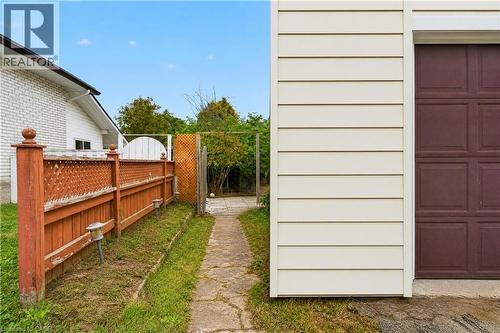 White brick exterior, horizontal siding, brown garage door, wood lattice fencing, concrete pathway - 176 Avalon Place, Kitchener, ON 
