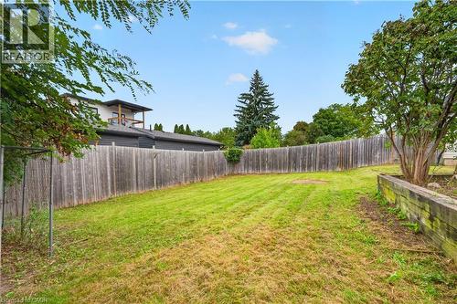 Expansive backyard featuring a wood fence, mature tree, and elevated planter box - 176 Avalon Place, Kitchener, ON 