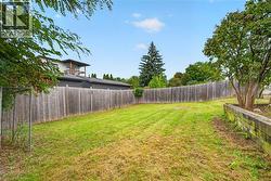 Expansive backyard featuring a wood fence, mature tree, and elevated planter box - 