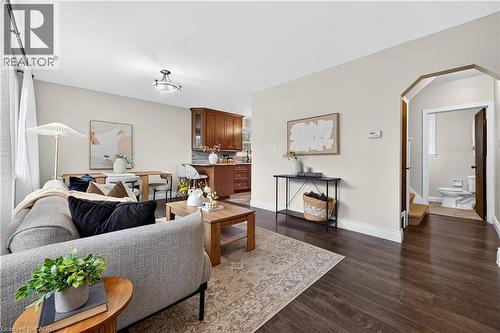 Dark wood-finish flooring throughout, light-colored wall paint, white trim, and a recessed archway - 176 Avalon Place, Kitchener, ON 