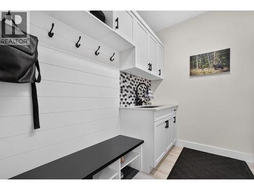 Functional mudroom off the garage with a built-in bench, storage, hooks and utility sink - 2400 Hawks Boulevard, West Kelowna, BC 