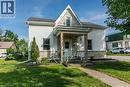Gabled roofline with asphalt shingles, white horizontal siding, stone veneer foundation, covered front porch, and front yard landscaping - 393 Huron Street, New Hamburg, ON 