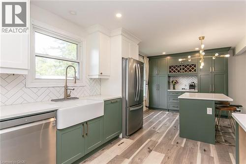 Updated kitchen featuring two-tone cabinetry, a farmhouse-style sink, a herringbone tile backsplash, and a central island with a countertop - 393 Huron Street, New Hamburg, ON 
