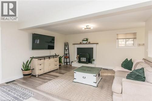 Spacious room featuring wood-finish flooring, a built-in fireplace, and overhead lighting - 393 Huron Street, New Hamburg, ON 