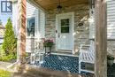 Front porch with wood-finish ceiling, stone veneer accent wall, white entry door with glass insert, and white siding - 393 Huron Street, New Hamburg, ON 