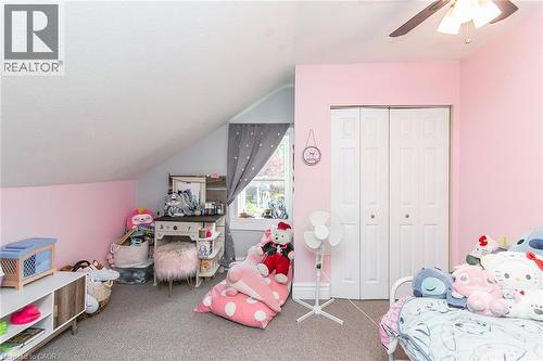 Sloped ceiling room featuring a window with curtain, built-in closet with bi-fold doors, and a ceiling fan - 393 Huron Street, New Hamburg, ON 