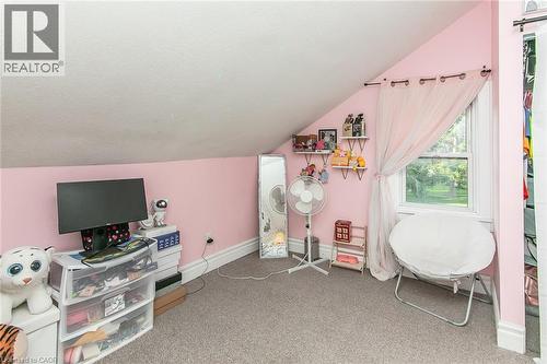 Angled ceiling room with neutral carpet flooring and a single window - 393 Huron Street, New Hamburg, ON 