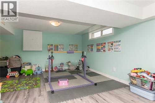 Finished lower level with wood-finish flooring, light fixture, and window - 393 Huron Street, New Hamburg, ON 