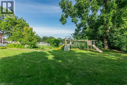 Expansive green lawn with mature trees and a wooden play structure - 393 Huron Street, New Hamburg, ON 