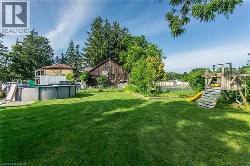 Expansive green lawn with an above-ground pool and a wooden play structure - 393 Huron Street, New Hamburg, ON 