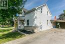 White siding exterior with a stone veneer foundation, covered front porch, gabled roofline, and attached carport - 393 Huron Street, New Hamburg, ON 