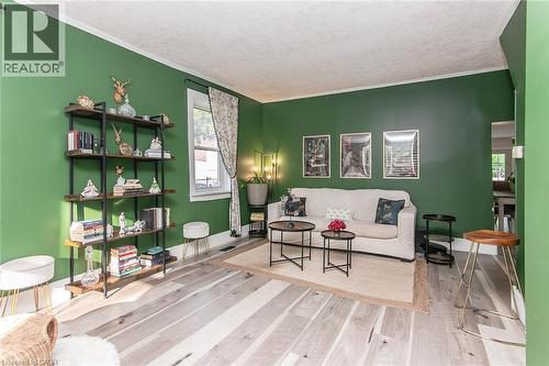Spacious living area featuring bright green walls, wood-finish flooring, and white crown molding - 393 Huron Street, New Hamburg, ON 