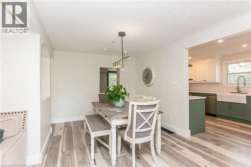 Wood-finish flooring throughout, with a recessed wall alcove and a modern linear chandelier - 393 Huron Street, New Hamburg, ON 