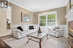 Hardwood trim accents with a chair rail and crown molding, brick fireplace with a white mantle, large windows, and carpet flooring - 