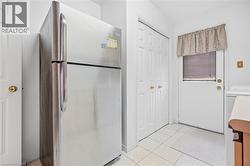 Stainless steel refrigerator, white paneled doors, and white tile flooring - 