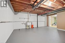Unfinished lower level featuring an exposed ceiling, concrete flooring, and a utility sink - 