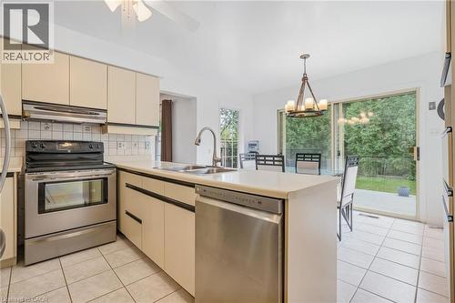 Kitchen featuring stainless steel appliances, light-toned cabinetry, tile flooring, and direct access to outdoor space via sliding glass doors - 5 Michelle Drive, St. Catharines, ON 