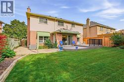 Expansive lawn with a multi-level deck, brick and siding exterior, green awnings, and mature perimeter fencing - 