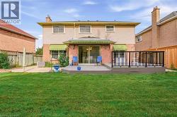 Expansive green lawn, multi-level outdoor deck with glass panel railing, sliding glass doors, and brick exterior with siding accents - 