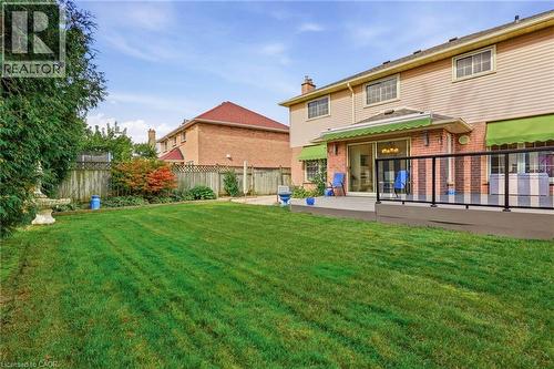 Expansive backyard featuring a manicured lawn, an elevated deck with glass railings, and a sliding glass door entry to the home - 5 Michelle Drive, St. Catharines, ON 