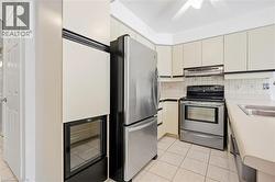 Stainless steel appliances, built-in beverage cooler, white cabinetry, tile flooring, and a white ceiling fan - 