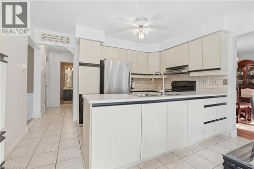 Kitchen featuring off-white cabinetry, stainless steel refrigerator, integrated range hood, tile flooring, and a ceiling fan - 5 Michelle Drive, St. Catharines, ON 