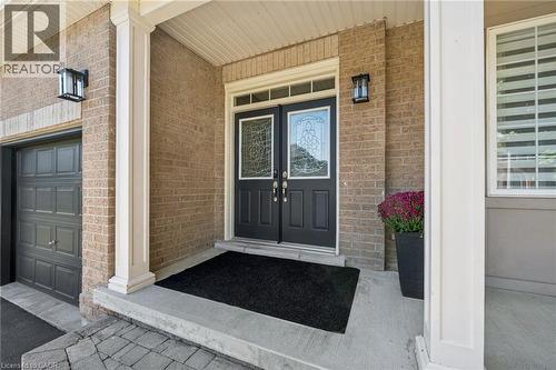 Brick exterior with a covered entry, double front doors featuring decorative glass, and a paneled garage door - 154 Falconridge Drive, Kitchener, ON 