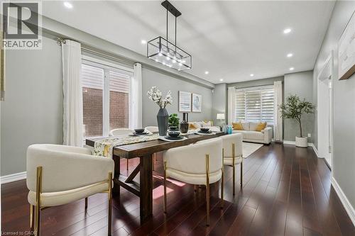 Open-concept living space featuring rich wood-finish flooring, recessed lighting, and a modern rectangular chandelier - 154 Falconridge Drive, Kitchener, ON 