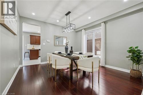 Dark wood-finish flooring, recessed lighting, and a linear pendant fixture illuminate this dining area - 154 Falconridge Drive, Kitchener, ON 