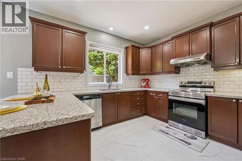 Kitchen with extensive wood cabinetry, granite-style countertops, stainless steel appliances, white subway tile backsplash, and recessed lighting - 154 Falconridge Drive, Kitchener, ON 