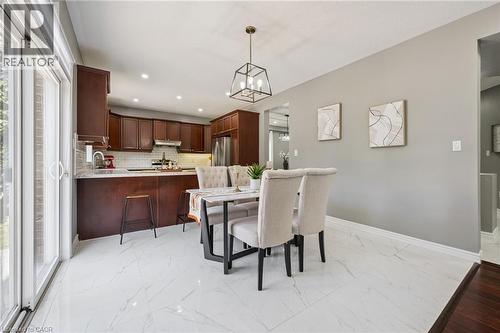Kitchen featuring dark wood cabinetry, a subway tile backsplash, and stainless steel appliances - 154 Falconridge Drive, Kitchener, ON 