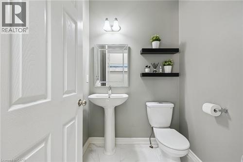 Pedestal sink with chrome faucet, wall-mounted mirror, and overhead vanity lighting - 154 Falconridge Drive, Kitchener, ON 