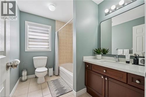 Bathroom featuring a vanity with a white countertop and wood-finish cabinetry, a rectangular mirror, and a bathtub with tile surround - 154 Falconridge Drive, Kitchener, ON 